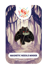 Mothman Needle Minder magnetic back magnet attached to cross stitch fabric on 14ct Aida