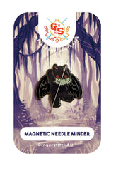 Mothman Needle Minder magnetic back magnet attached to cross stitch fabric on 14ct Aida