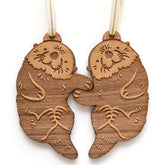 Otters hand-holding design on wood ornament pair