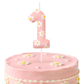 Pink number 1 birthday candles with daisy themed cake topper on a cake