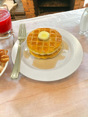 Two 4x4 inch faux waffles with syrup and butter on a 7 inch plate decorative prop