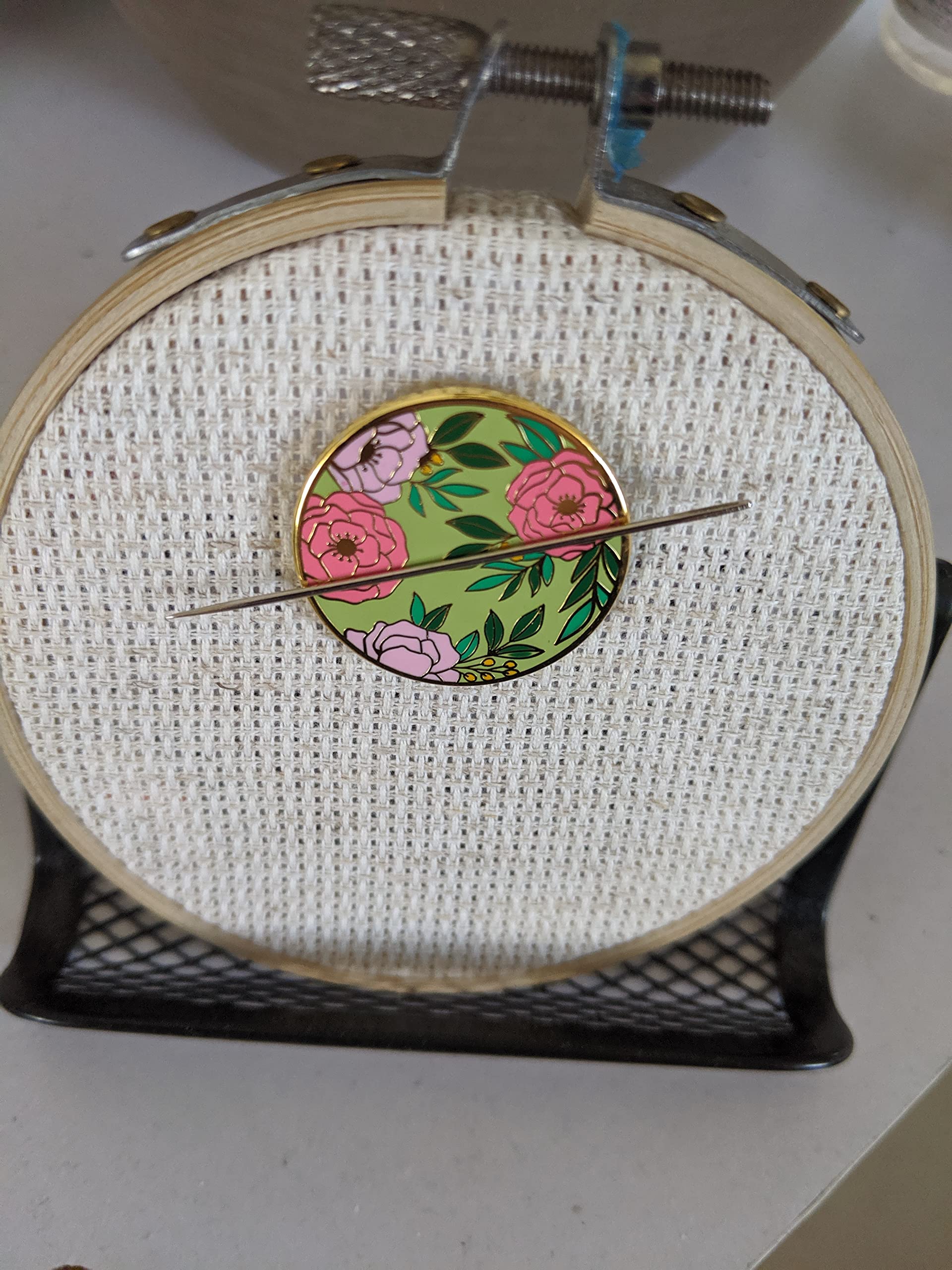 Needle Minder securing needle on fabric on embroidery hoop
