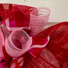 Front door decor wreath with pink and red heart ribbons