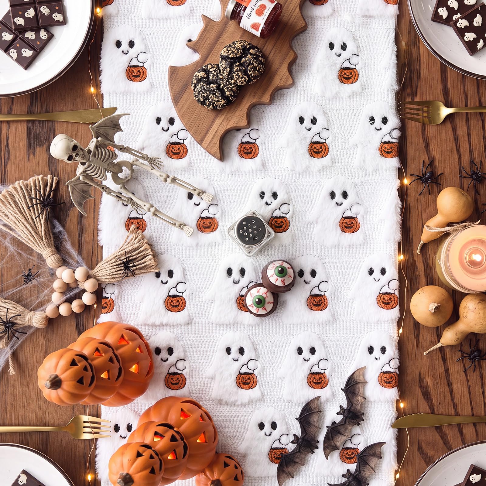 3D plush ghosts holding pumpkin baskets on Halloween table runner