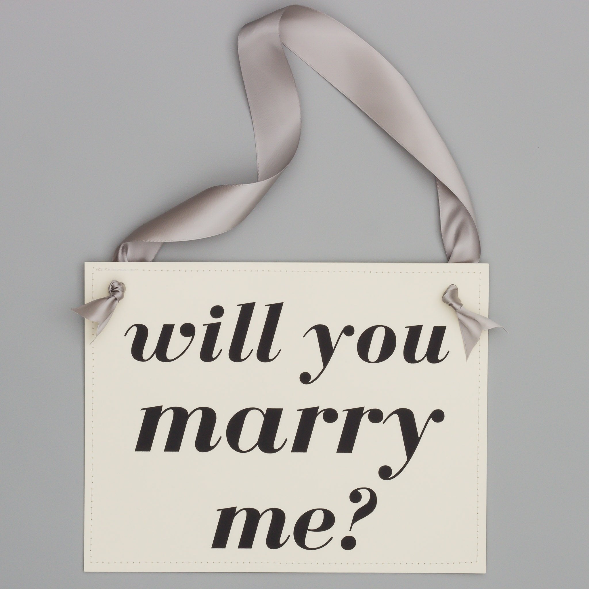 Hand tied satin ribbon around elegant proposal sign