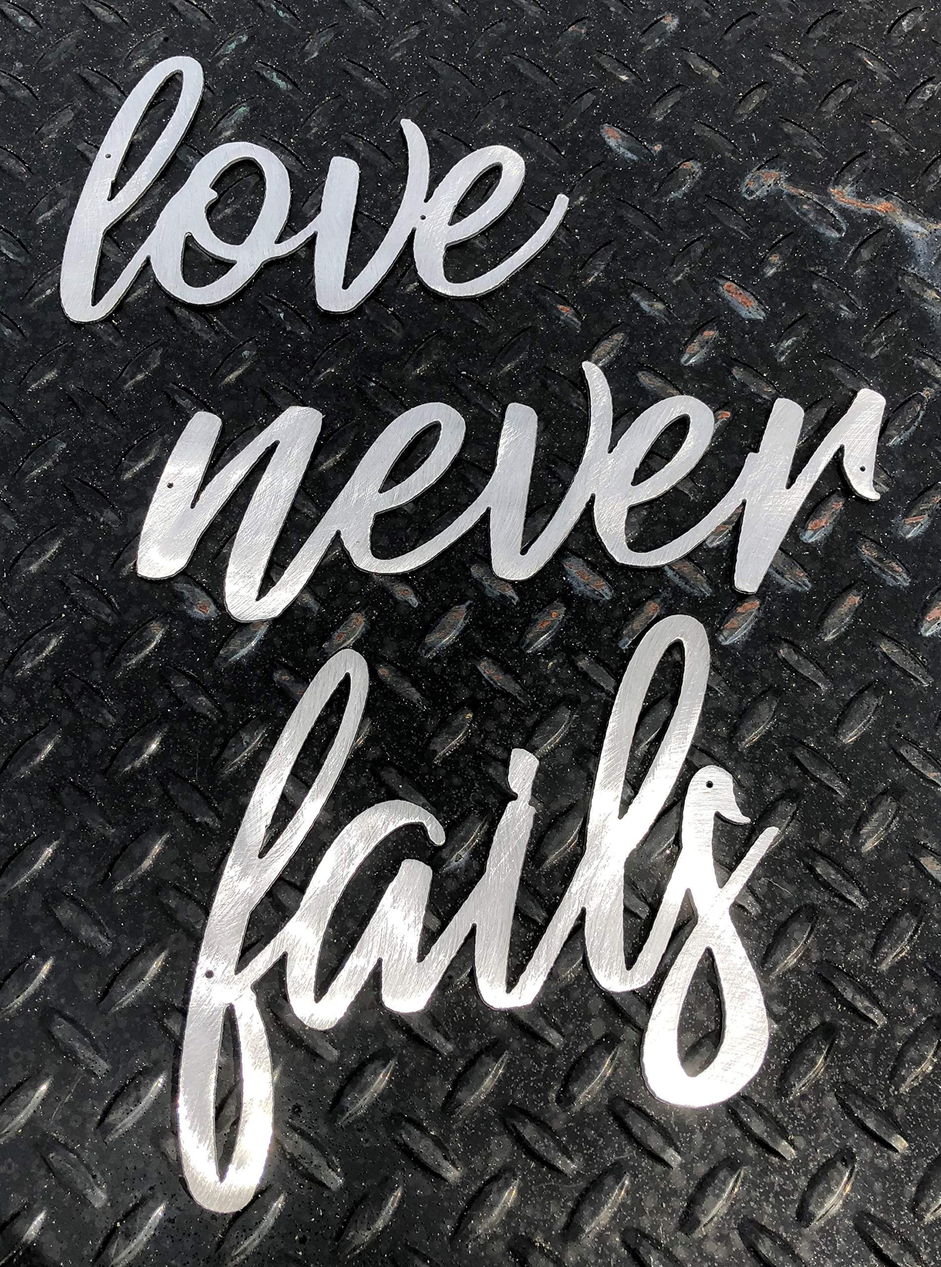Three word panels display for Love Never Fails metal wall art accents