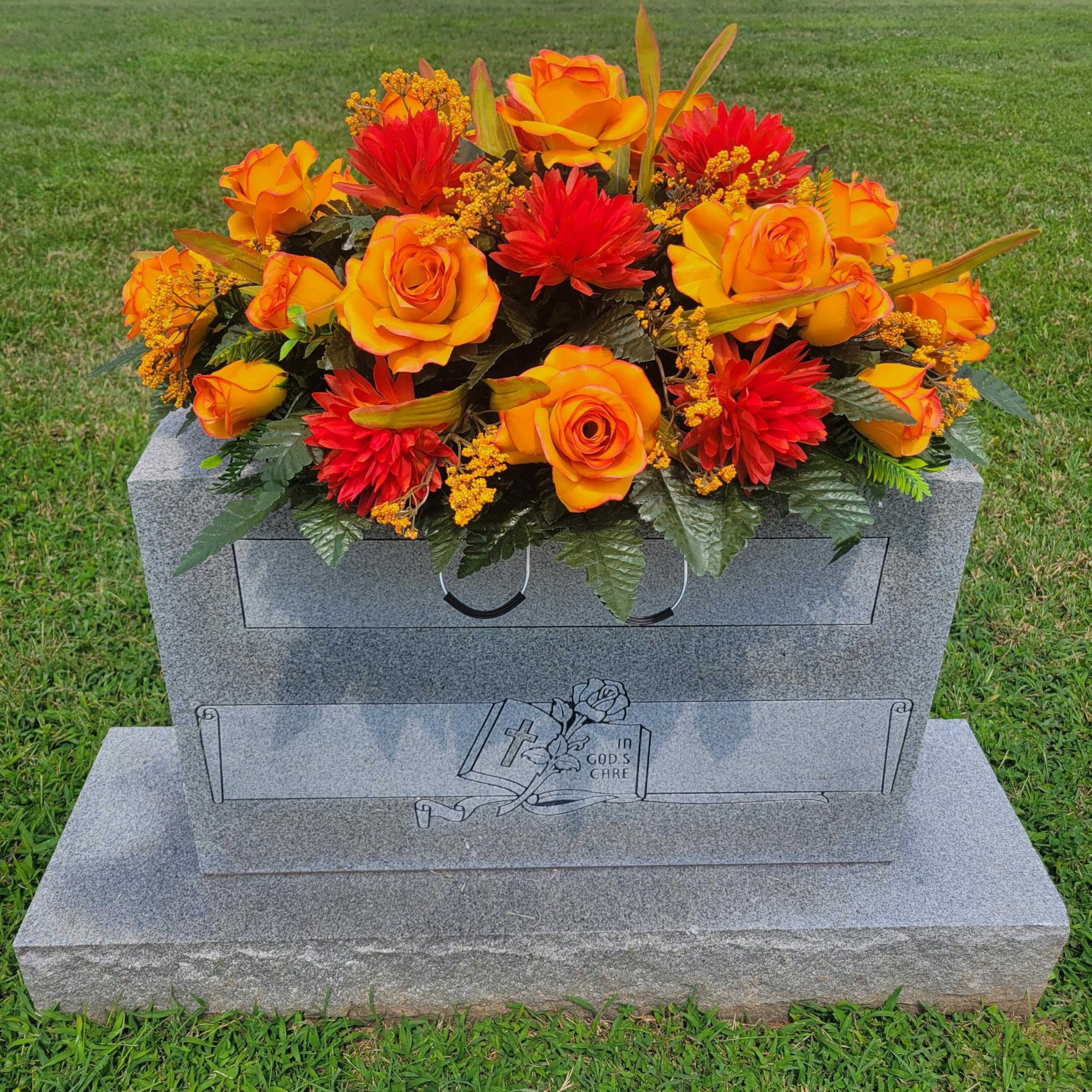 Orange roses and mums among faux silk grave flowers for headstone display