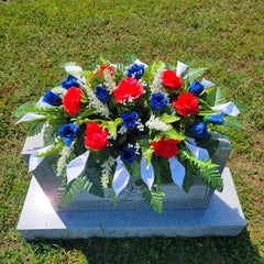 Silk roses and calla lilies on a four-legged metal headstone saddle