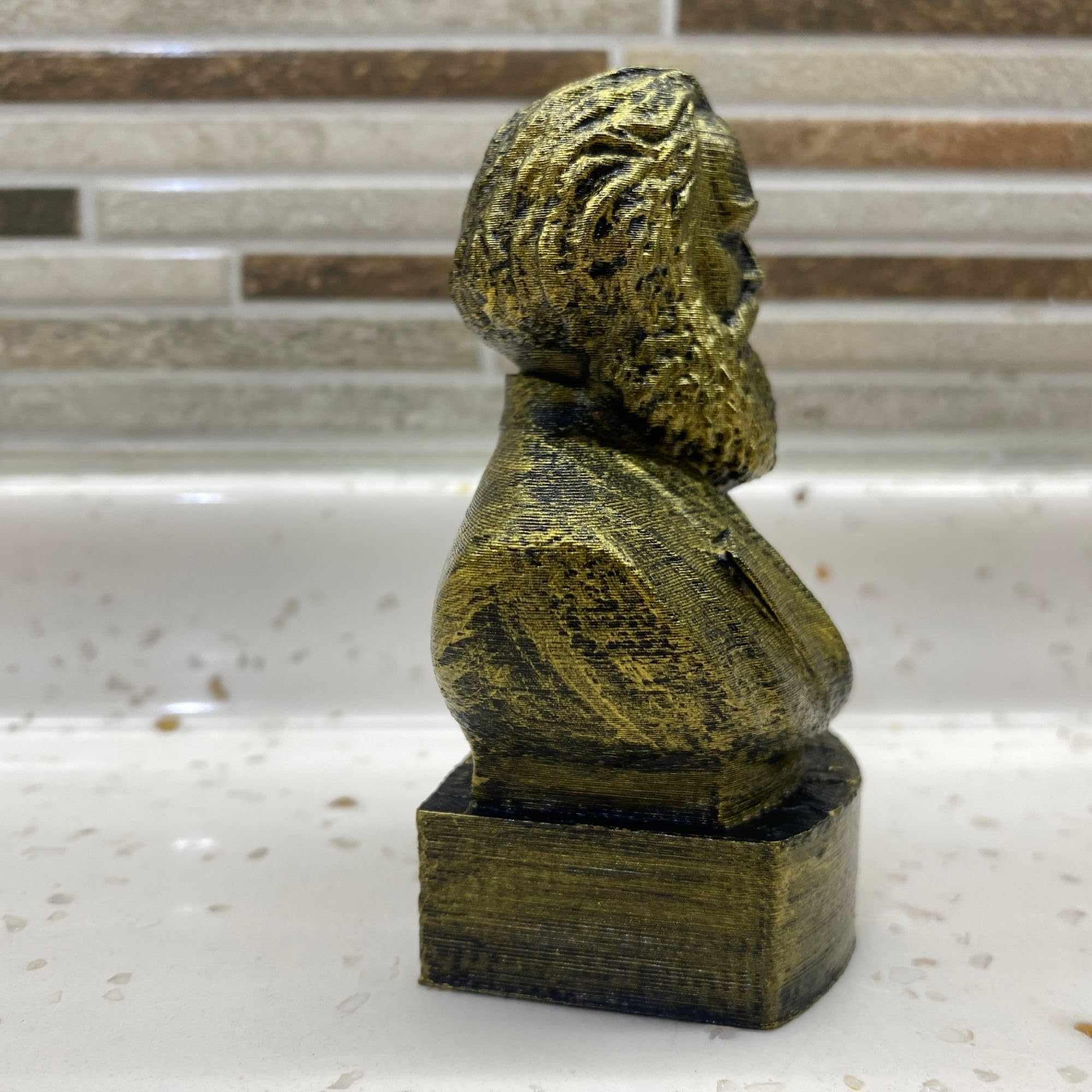 Gold finished Karl Marx bust statue on display shelf