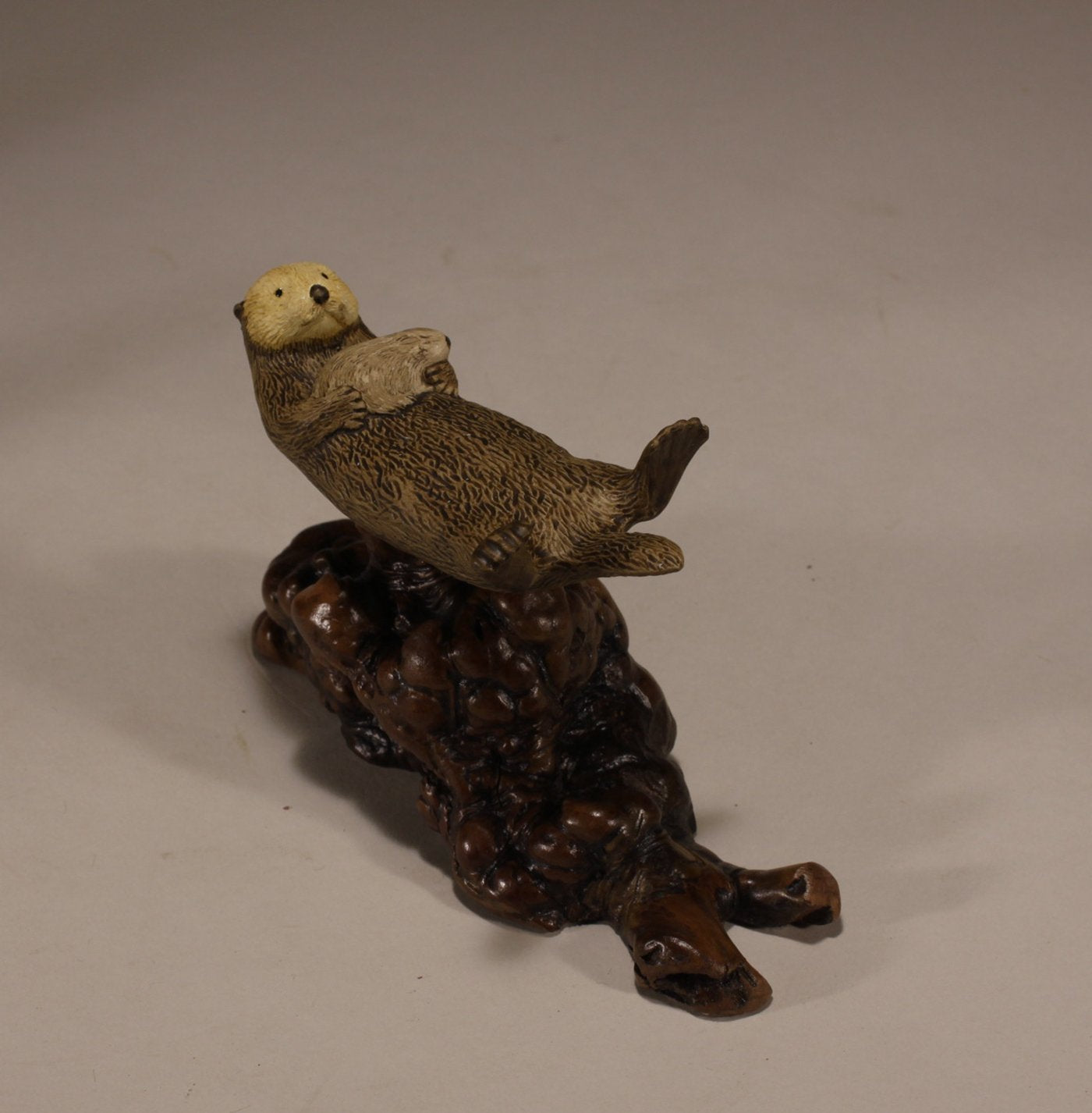 Polished manzanita burl base supporting resin sea otter statue
