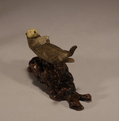 Polished manzanita burl base supporting resin sea otter statue