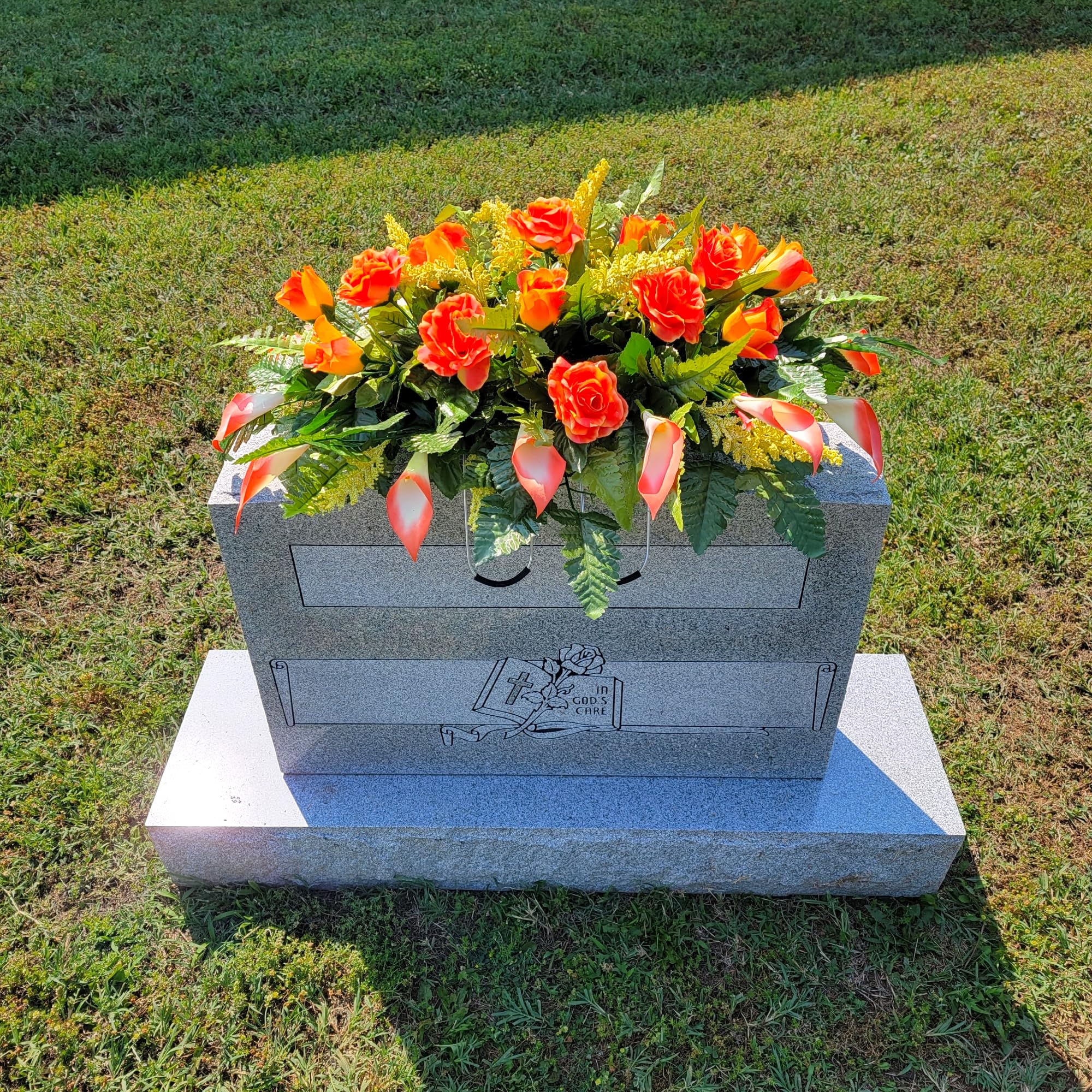 Headstone decorating display featuring orange roses and calla lilies