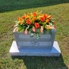 Headstone decorating display featuring orange roses and calla lilies