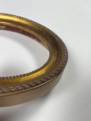 Handleafed gold ornament on oval frame