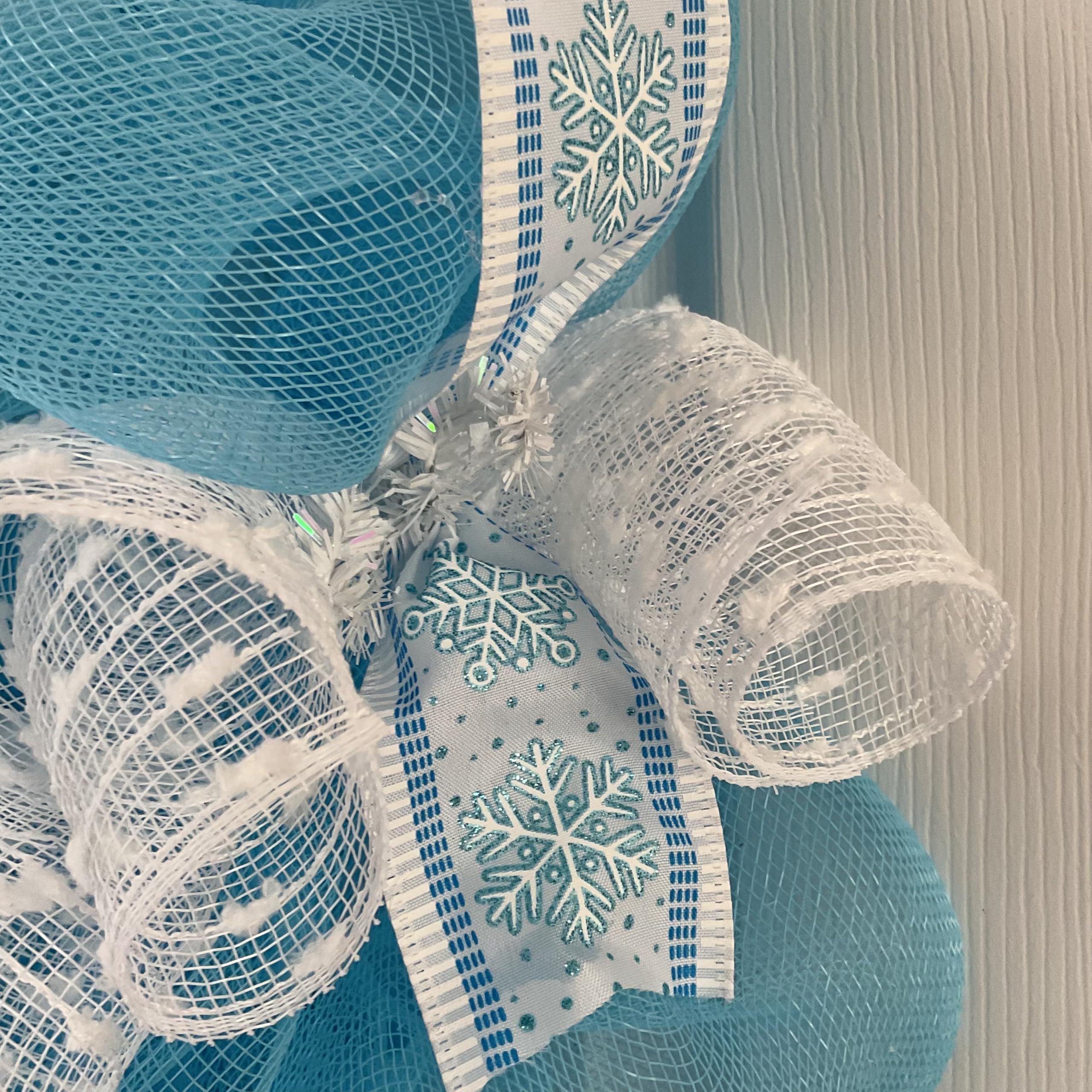 Turquoise snowflake ribbons accenting wreath edge