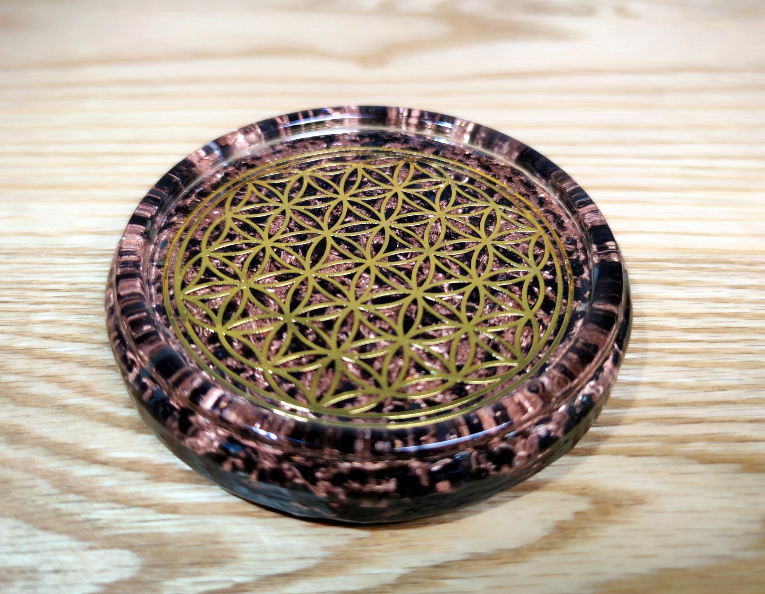 Copper chips and metal Flower of Life symbol on coaster materials